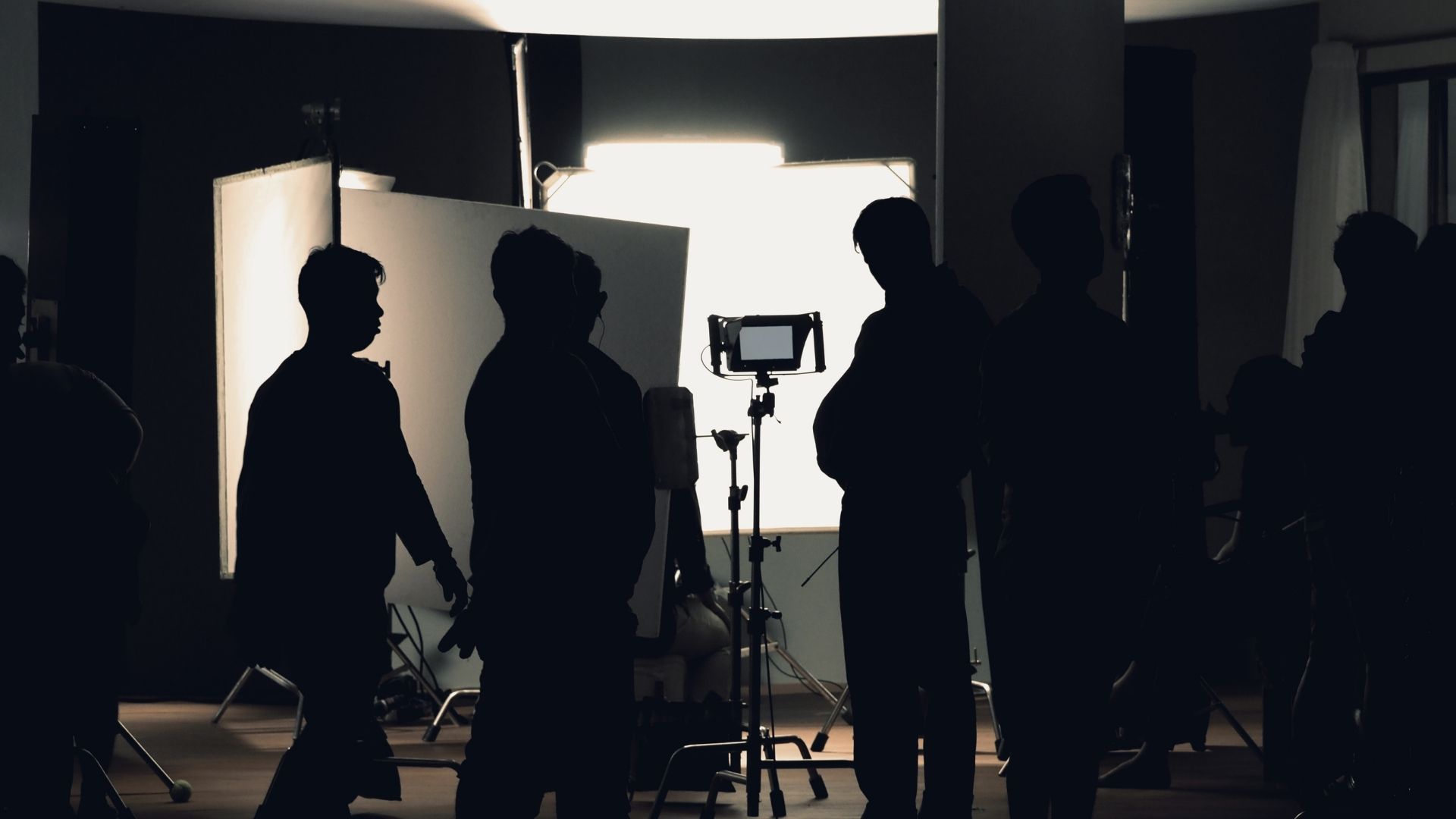 Silhouetted crew walking across a dark studio floor with bounce boards