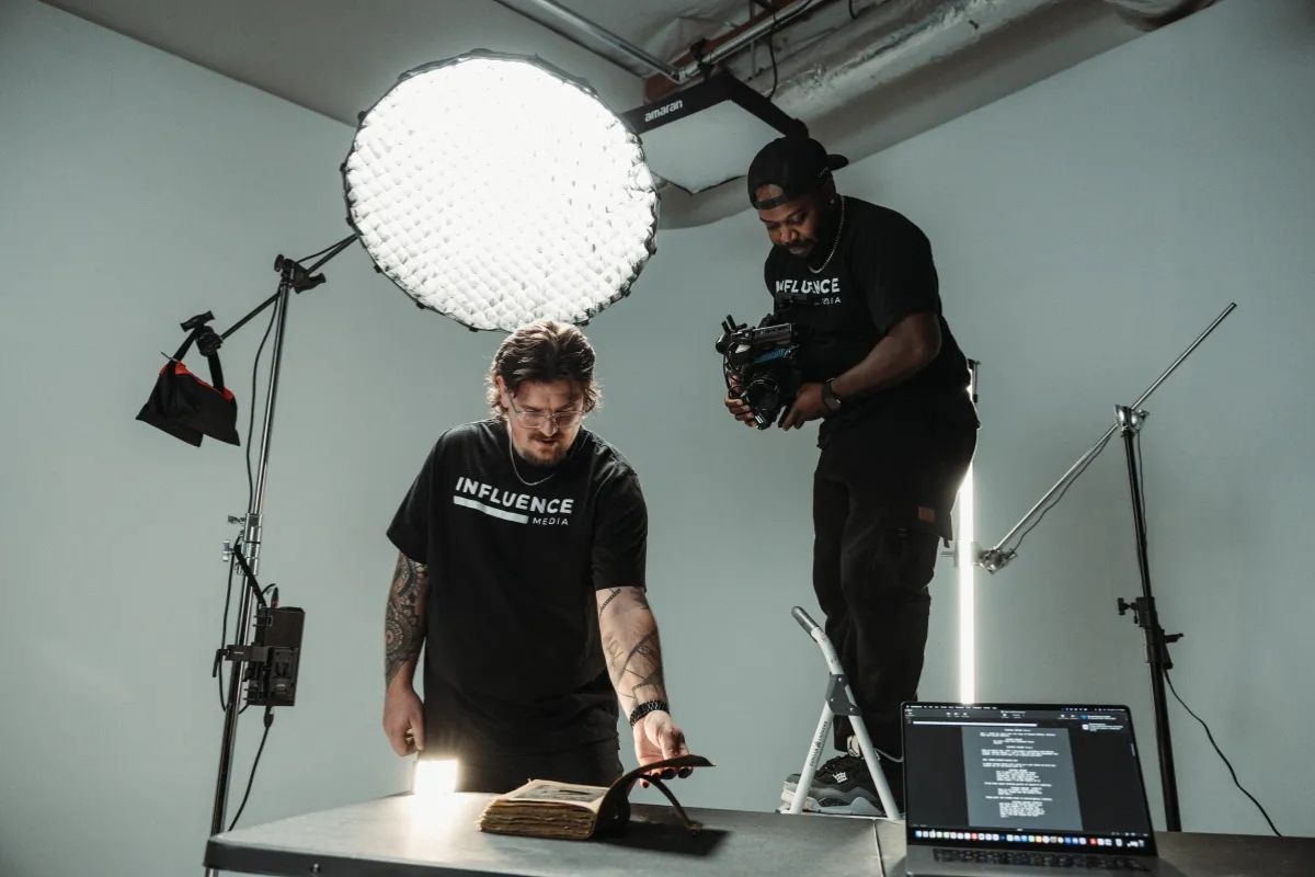 Two crew members shooting a tabletop product setup under a large softbox